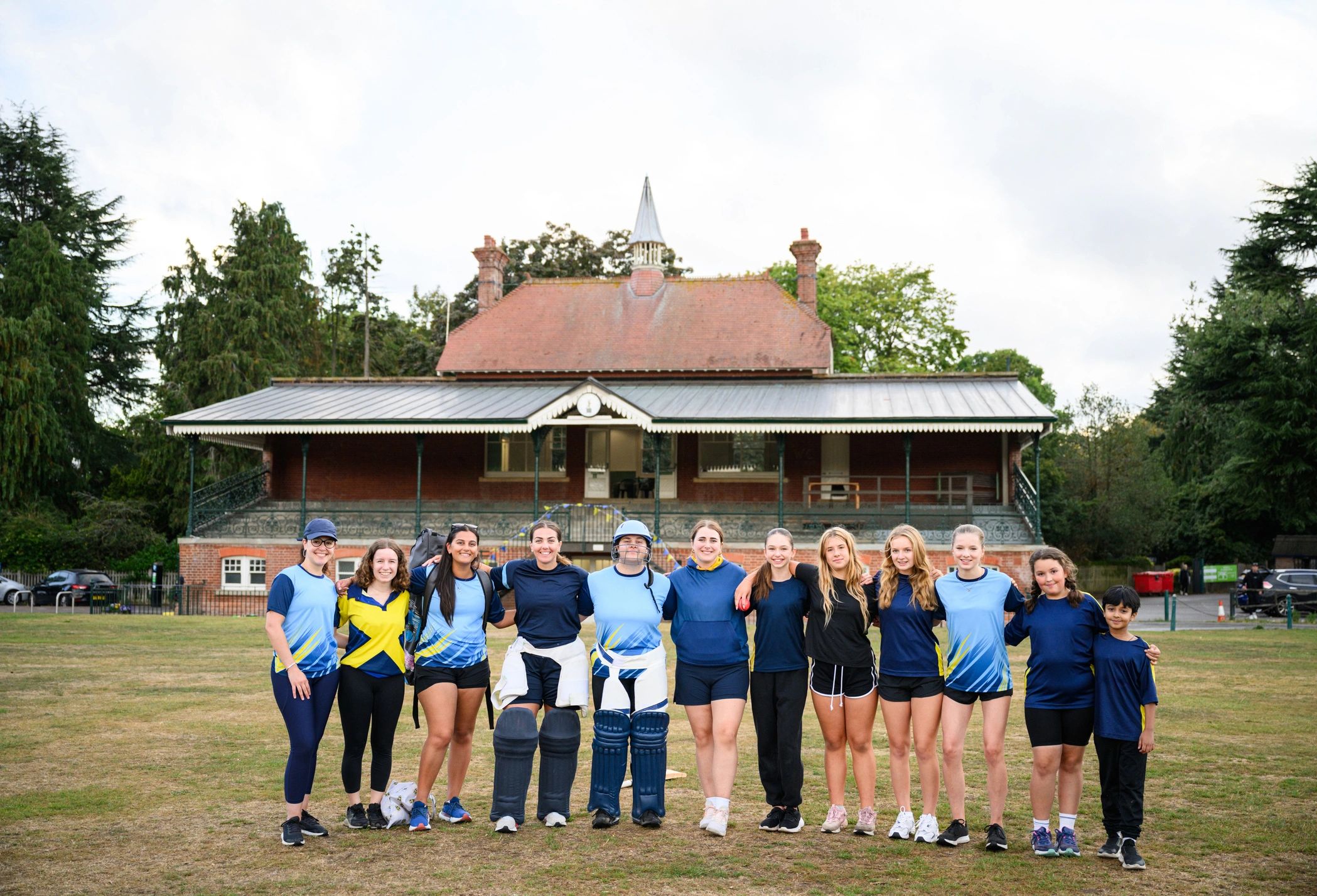 Women and girls cricket team standing together on a field