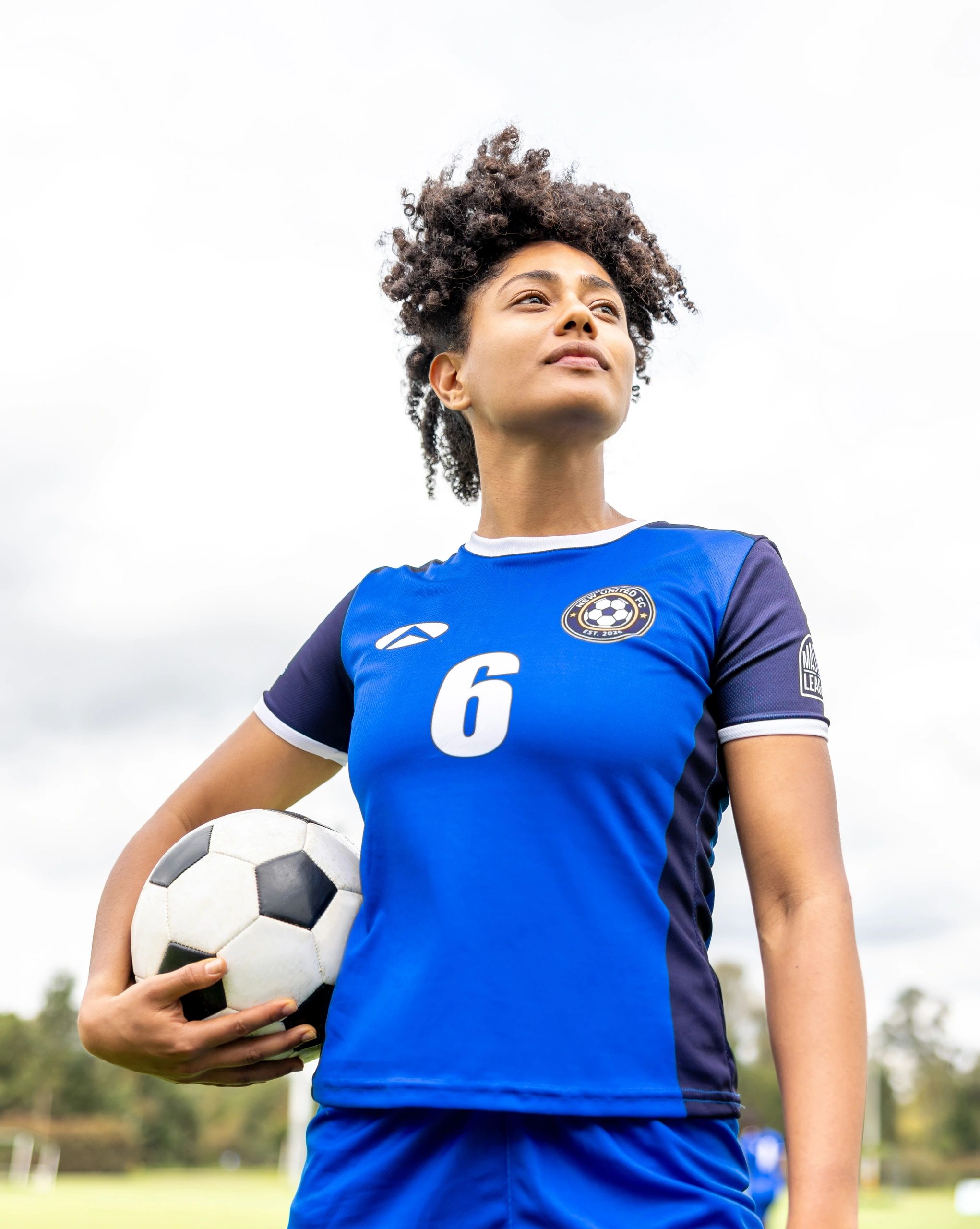 Female soccer player holding a ball on a field